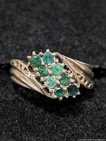 Close-up front angle of the sterling silver ring showing the emerald cluster design with multiple green stones in a flowing silver setting.