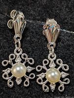 Close-up front view of both sterling silver freshwater pearl earrings showing ornate filigree and central pearl.