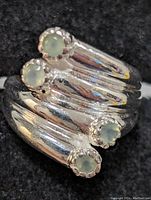 Close-up photo of sterling silver ring with four pale green round gemstones arranged on quadruple bands.