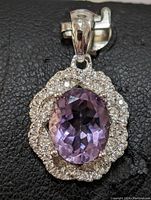 Close-up front view of the sterling silver amethyst pendant showing the purple oval amethyst center and double halo of small clear stones.