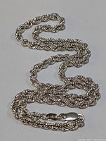 Full length of sterling silver rope chain laid out on white background, showing twisted rope link pattern and finished ends.