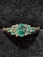 Front view showing central oval emerald and smaller surrounding emerald stones on the sterling silver band.