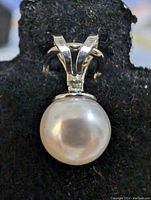 Close-up front view of the sterling silver pendant with a round freshwater pearl mounted on it, showcasing the pearl's surface and the bail's design.