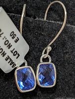 Front view of one sterling silver earring with rectangular faceted blue quartz gemstone attached to a curved hook.