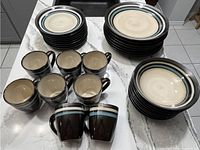 Top view showing stacks of large dinner plates, small plates, and mugs arranged on a counter.