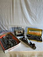 Full view of entire lot including wood plane, electric sharpener, and two socket sets, one in box and one in metal case