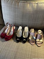 Three pairs of ladies shoes (red, black, pink) displayed on couch showing style and condition.
