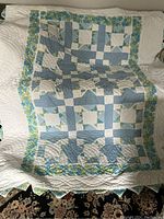 Full view of quilt front showing blue and white patchwork with floral border
