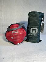 Red McKinley Traveller Light 900 sleeping bag and green Outbound air mattress packed in carry bags