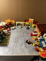 Wide view of Little People hospital building sections and scattered accessories including beds, vehicle, figures