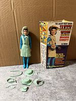 Full view of Janice West doll beside original box with accessories arranged in front