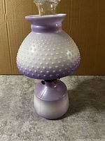 Front view of vintage hobnail glass oil lamp with purple and white gradient shade and base.