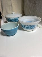 Photo of six vintage Pyrex pieces showing blue floral pattern on white glass. Includes nesting bowls and covered casserole dish.