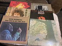 Top view of 6 album covers partially overlapping. Visible are Otis Redding - The Dock of the Bay, Neil Young - Live Rust, and others.