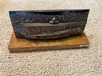 Photo showing side view of bronze or brass cityscape sculpture mounted on marble base with artist plaque