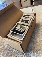 Open box filled with a large number of loose black and white photos mostly visible with white borders.
