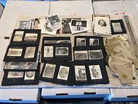 Full layout of old photographs and albums from the box showing a variety of mounted and loose photos of varying sizes.