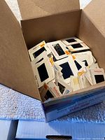 Box of many vintage Kodak photo slides in cardboard mounts, mostly white with orange/yellow Kodak branding visible on slides.