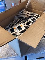 Open cardboard box filled with hundreds of 35mm photographic slides in cardboard mounts, mostly Kodachrome branding visible.