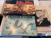 Top view showing all three board games side by side: Axis & Allies, Fighter-Bomber, Luftwaffe, all with worn boxes.