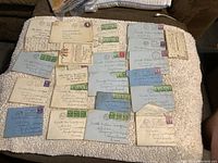 Full lot of 19 WWII vintage envelopes and letters arranged on a beige blanket, mostly addressed to Private William Montgomery with various stamped postmarks and addresses.