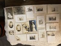 Image showing 15 vintage postcards laid out on a white textured surface, mostly photographic portraits of individuals and groups, some handwritten notes visible.