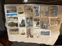 Photo showing 18 postcards laid out on a blanket, featuring various black and white and color vintage images.