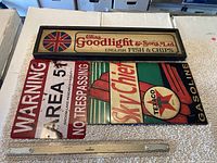 Four vintage wooden and metal signs displayed with a measuring ruler for scale.