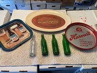 Overview photo of three advertising trays and four old bottles on a table.