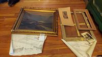 Wide shot of the oil painting, wooden frames, and vintage prints on wooden floor