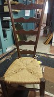 Front view of the wooden ladder back chair with woven seat.