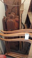 Wood pieces including curved slats or chair backs leaning against flat wood panels and shelving boards.