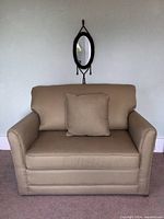 Front view of taupe La-Z-Boy armchair with throw pillow on carpeted floor