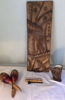 Overall view of the lot showing hand-carved wooden art, maracas, ceramic harp vase, and sliding instrument