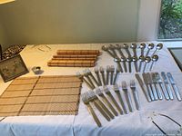 Full view of stainless steel flatware arranged on table with bamboo mats