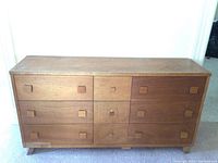 Full front view of mid-century style wooden dresser with 9 drawers and square wooden knobs.