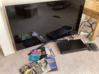 Samsung 48-inch TV with Panasonic DVD player and DVDs in front on carpeted floor