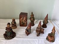 All 7 Tom Clark gnome figurines and a wooden block with bird artwork arranged on white surface