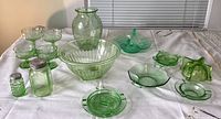 Photo displaying the entire assortment of vintage green glass including stemware, swan bowl, vase, shakers, and various dishes on a white tablecloth.