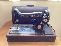 Front side of the vintage Singer sewing machine mounted on a wooden table showing the machine body, handwheel, and needle area.