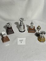 Wide view of full set of 6 McDonald's NHL hockey trophies including Stanley Cup replica, showing size, shapes and detail of each trophy on white background.