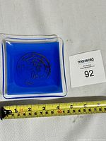 Full view of blue glass ashtray showing size with measuring tape.