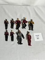 Nine Star Trek action figures on a white sheet, showing various Starfleet officers and alien characters.