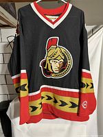 Front view of Ottawa Senators black alternate hockey jersey showing logo, colors, and overall condition including worn collar and patch.