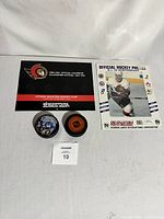 Photo showing the hockey puck signed by Alex Daigle, official 1993-1994 Ottawa Senators calendar, unsigned hockey puck, and 8x10 glossy photo.