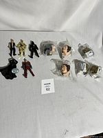 Various small Star Wars plastic action figures and five character heads sealed in plastic bags, all laid on a white cloth background.
