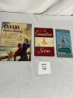 Photo showing three vintage Canadian tourist booklets including Canada Vacations Unlimited, The Canadian Scene, and Canada Tourist Map Book (Ottawa) laid flat on white cloth background.