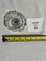 Glass ashtray with measuring tape indicating approximately 4 inches diameter placed below it.