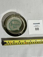 Top-down photo of round glass ashtray with measuring tape indicating size approximately 4 inches in diameter.