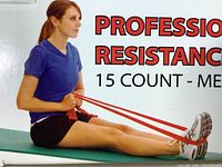 Woman demonstrating use of red resistance band by looping it around foot for exercise, sitting on bench.